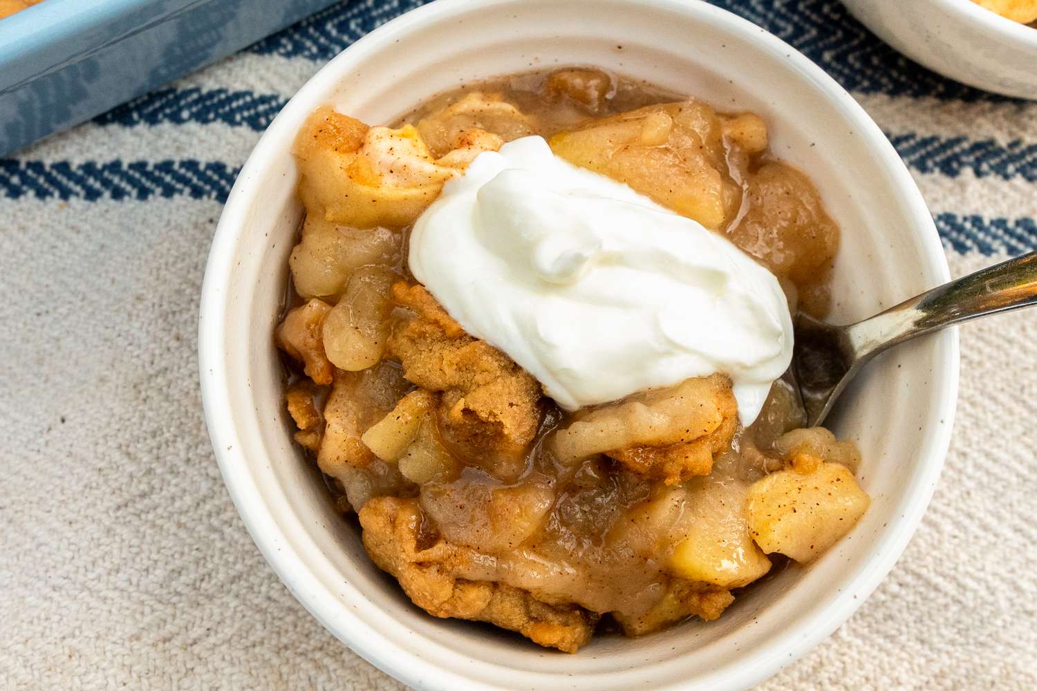 A bowl of apple cobbler with whipped cream on top