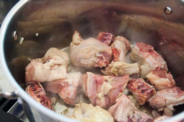 Chicken pieces cooking in a stock pot with onions