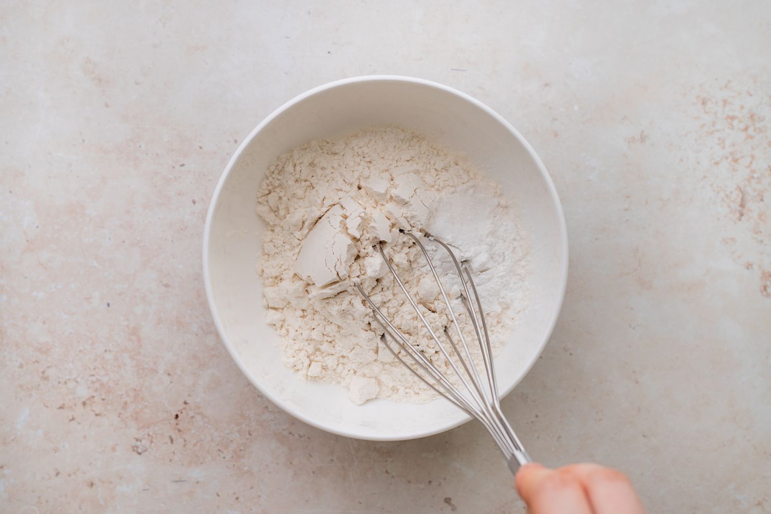 Whisking dry ingredients in a bowl to make chocolate chip cookies.