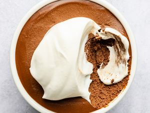 Mocha mousse in a bowl with whipped topping, a portion scooped out