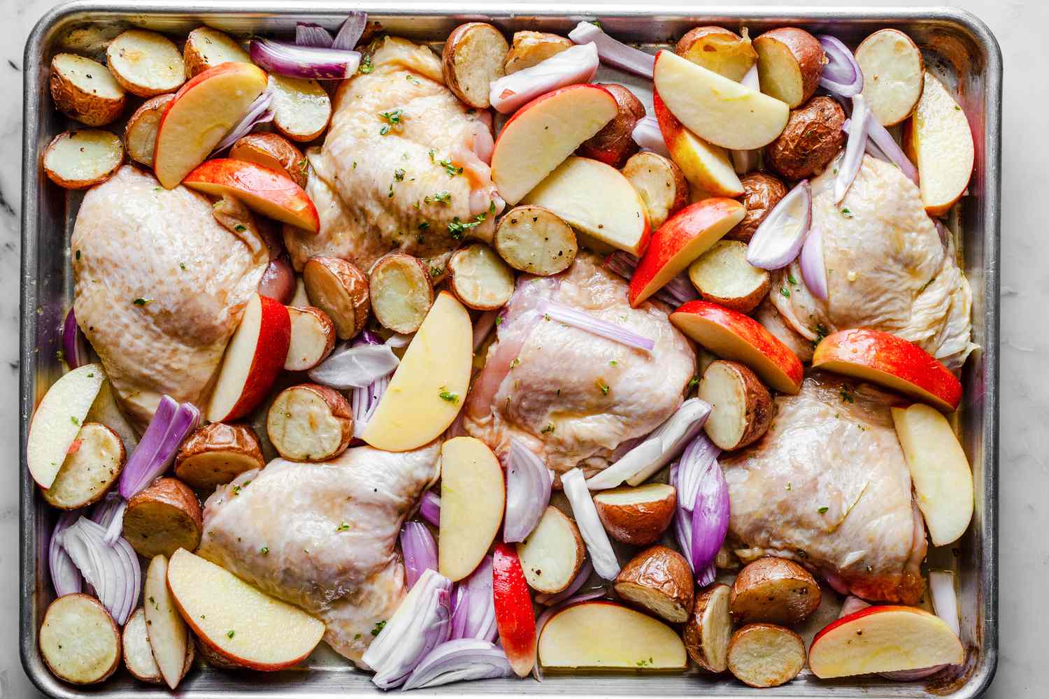 Ingredients for Sheet Pan Honey Roasted Chicken Thighs with Baby Potatoes, Apples, Shallots, and Thyme Recipe on Tray