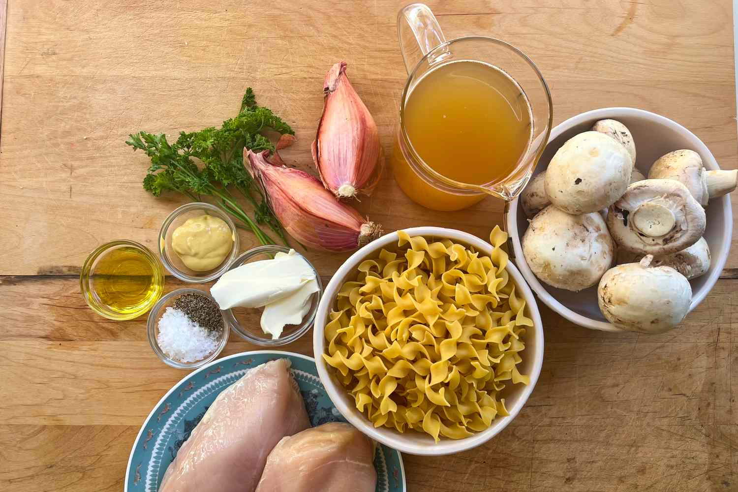 Ingredients including chicken breasts mushrooms dry egg noodles shallots parsley olive oil butter and a cup of broth
