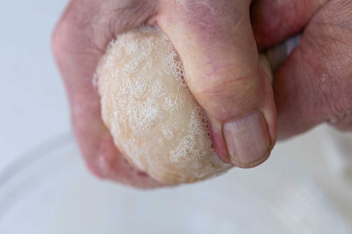 Close up of hands squeezing out moisture from the shaved potatoes