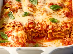 A baking dish with lasagna rollups topped with melted cheese and basil leaves