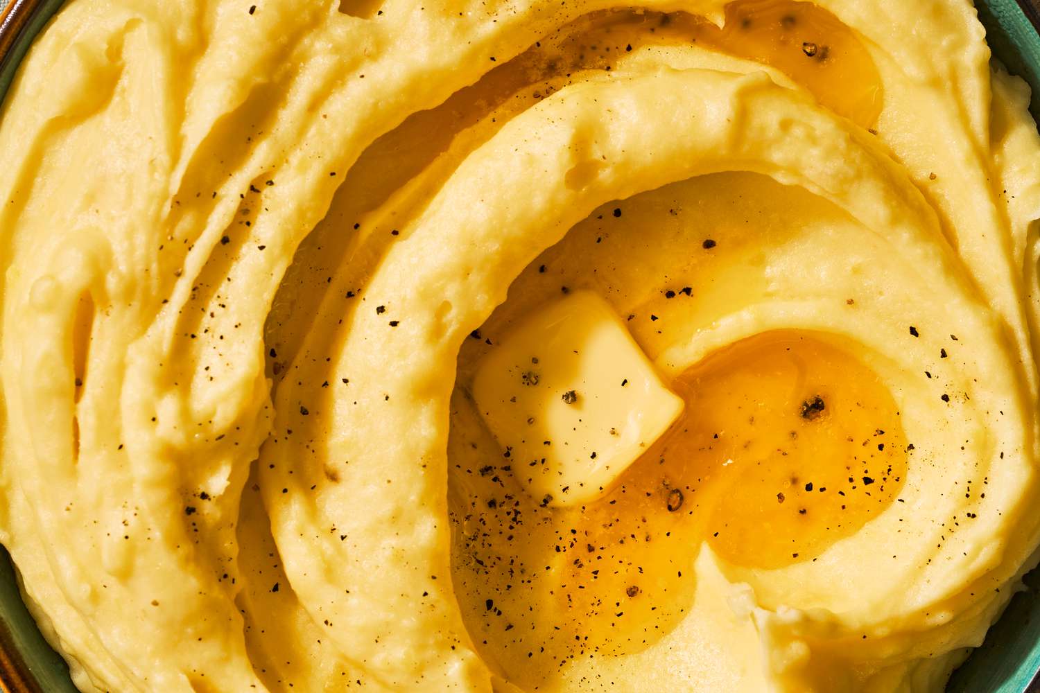 Close-up of a bowl of very creamy mashed potatoes with a pat of butter melting on the top