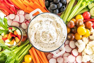 A crudités spread with a dip bowl of ranch dip in the middle
