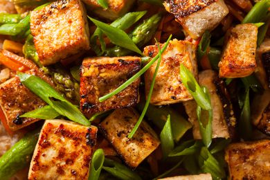 Closeup of crispy cooked tofu cubes and sliced scallion