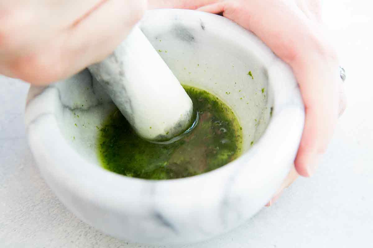 Add the remaining rum for the mojito drink to the mortar and pestle and let the mixture steep