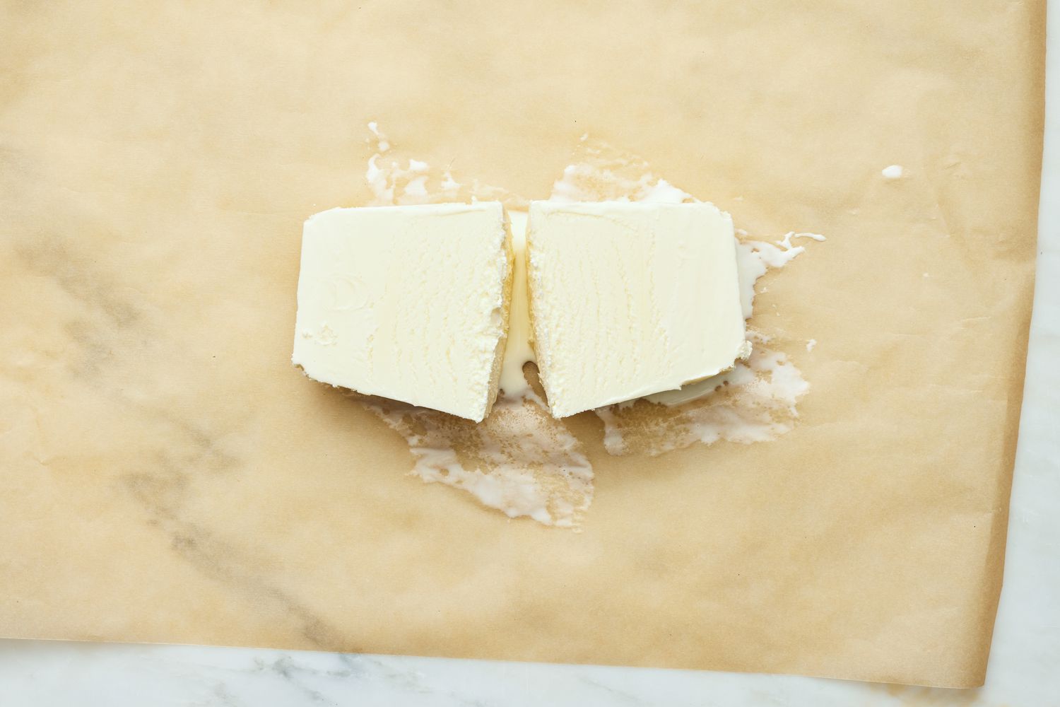 Slightly Softened Vanilla Ice Cream (Still Shaped Like a Pint Container) Cut in Half and Placed on a Piece of Parchment Paper 