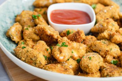 A serving tray with homemade chicken nuggets and ketchup on it.