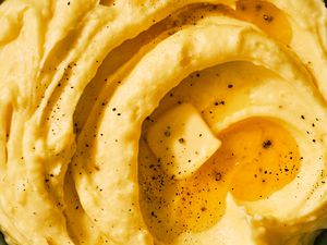 Close-up of a bowl of very creamy mashed potatoes with a pat of butter melting on the top