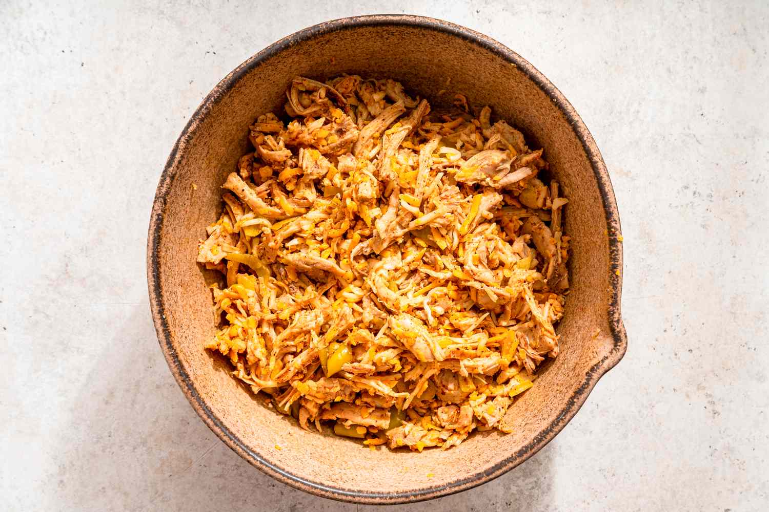 Bowl of shredded chicken mixed with spices for chicken taco casserole recipe