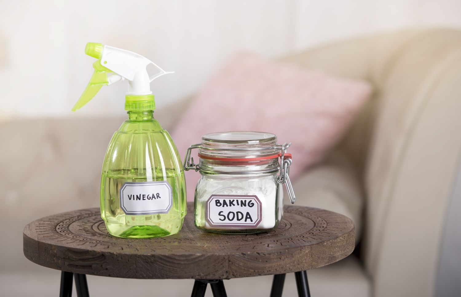 Using baking soda Sodium bicarbonate and white vinegar for home cleaning. White vinegar in spray bottle and baking soda in glass jar.