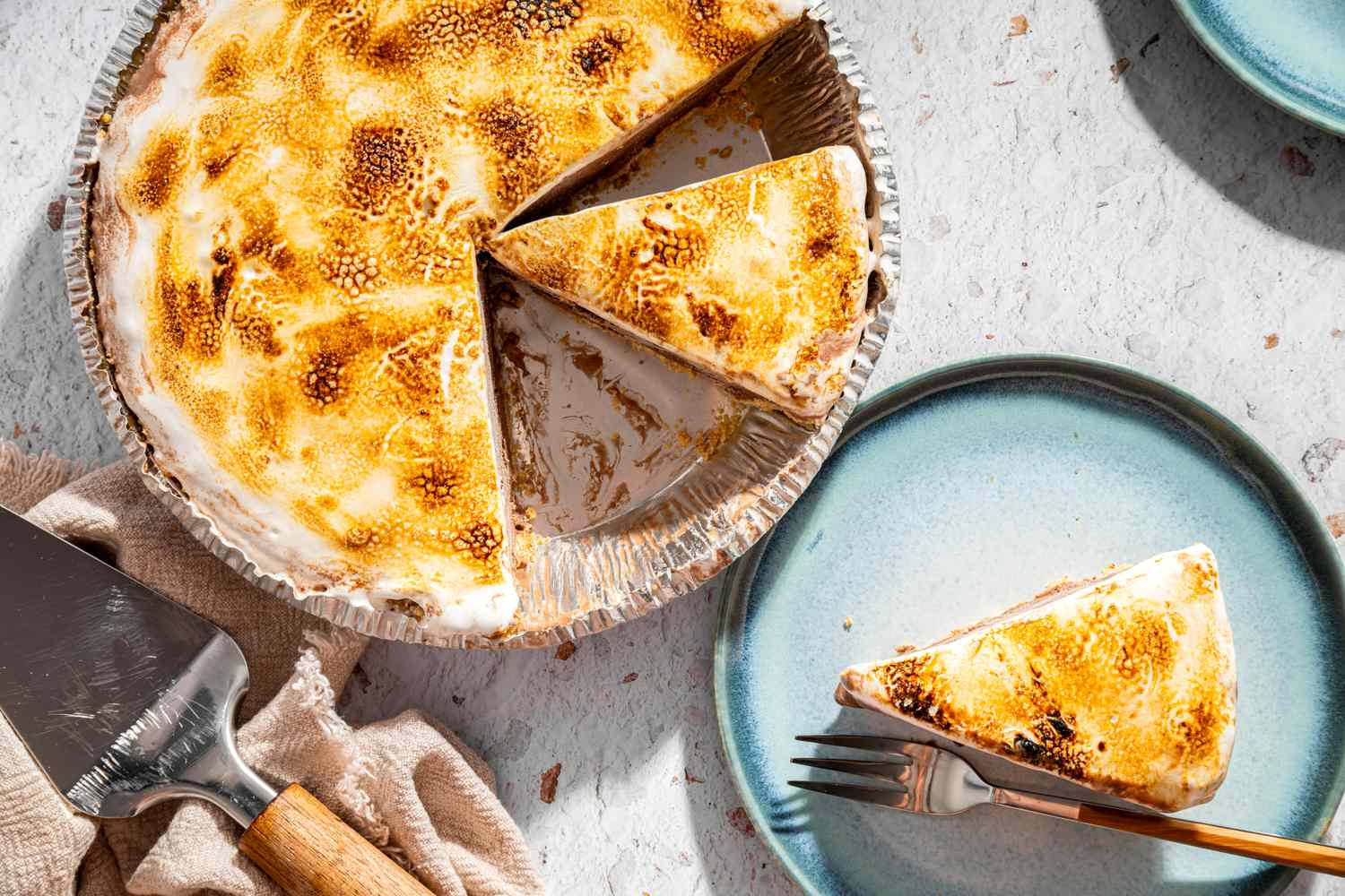A frozen smores pie with a missing slice served on a blue plate