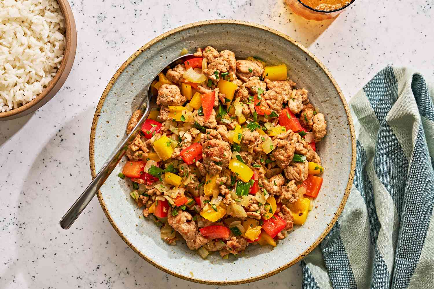 A serving bowl of cooked ground turkey and peppers with white rice on the side