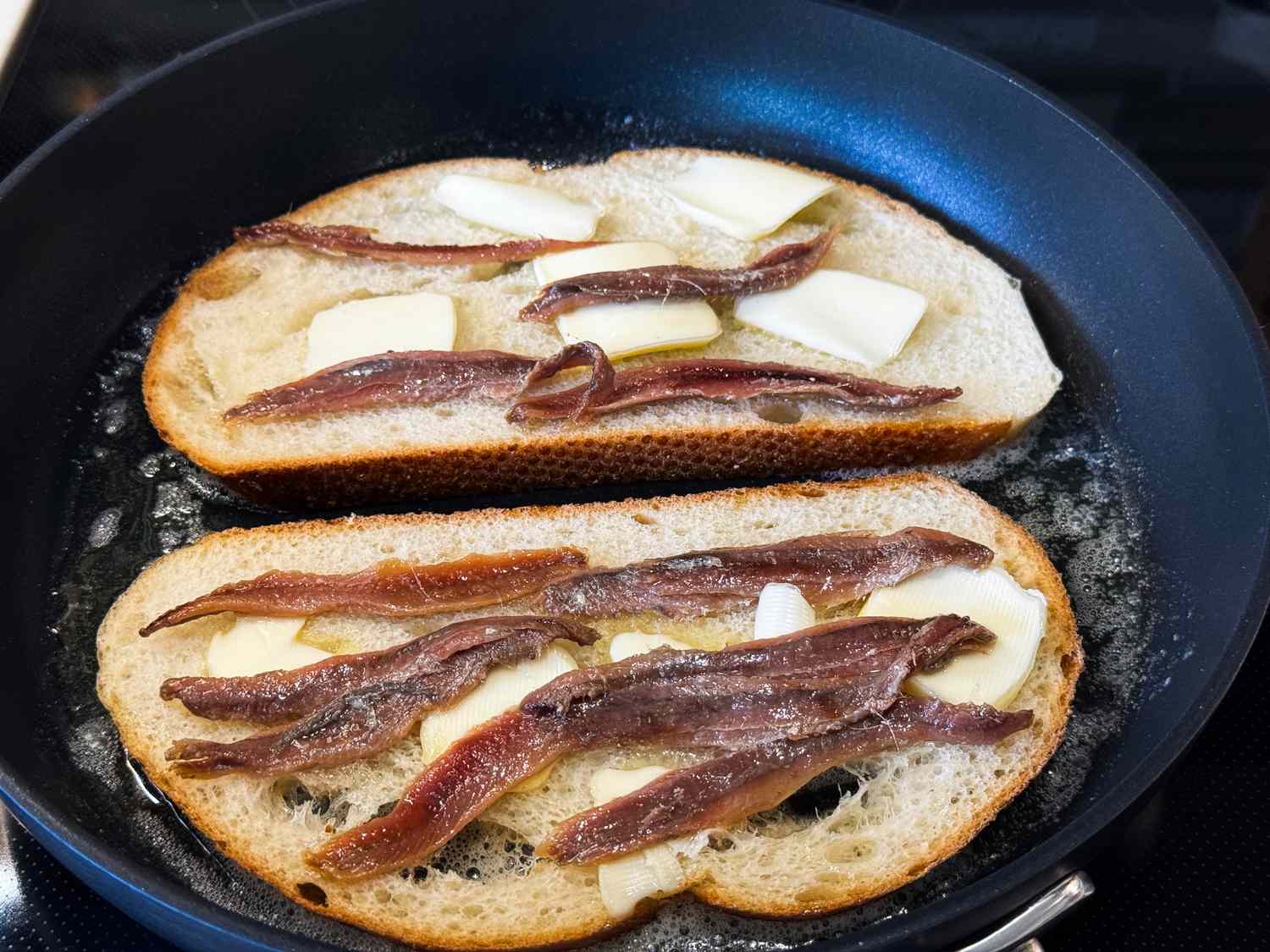 toast with anchovies on a buttered skillet
