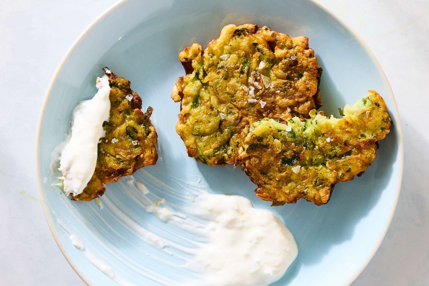 Zucchini fritters served on a plate with a dollop of yogurt sauce