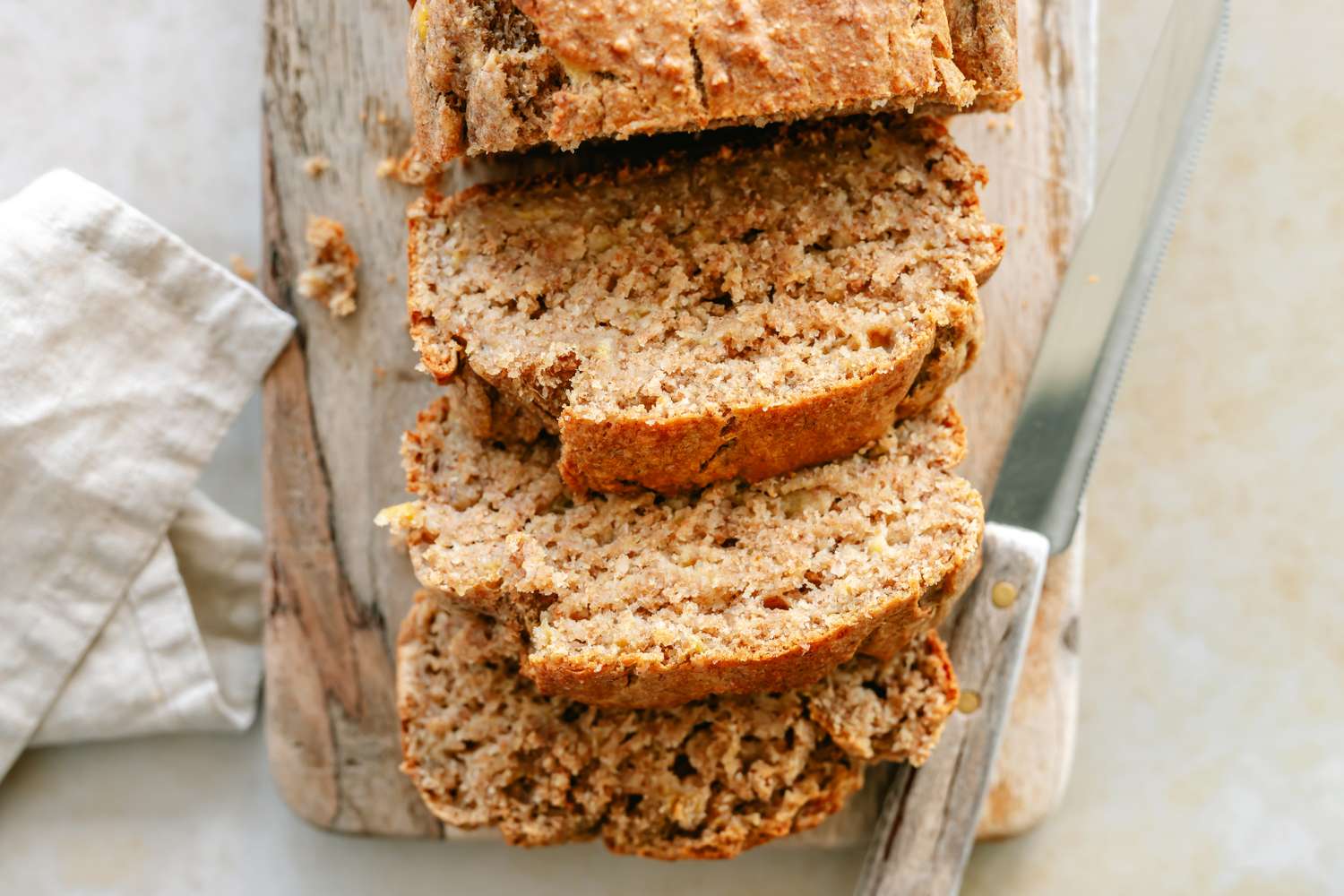 Sliced banana bread on a wooden board with a knife placed beside it