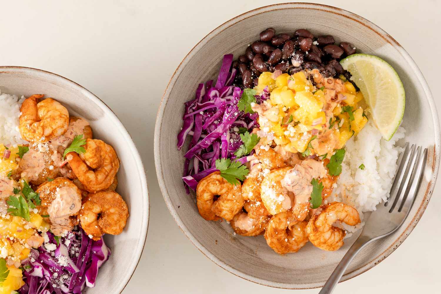 Two bowls of shrimp with rice, black beans, and vegetables