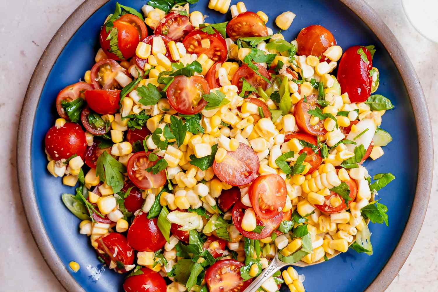 A plate of corn and tomato salad with herbs