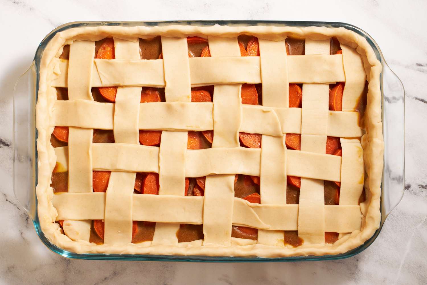Sweet potato sonker with a lattice style crust placed in a rectangular glass baking dish prepared and ready for baking