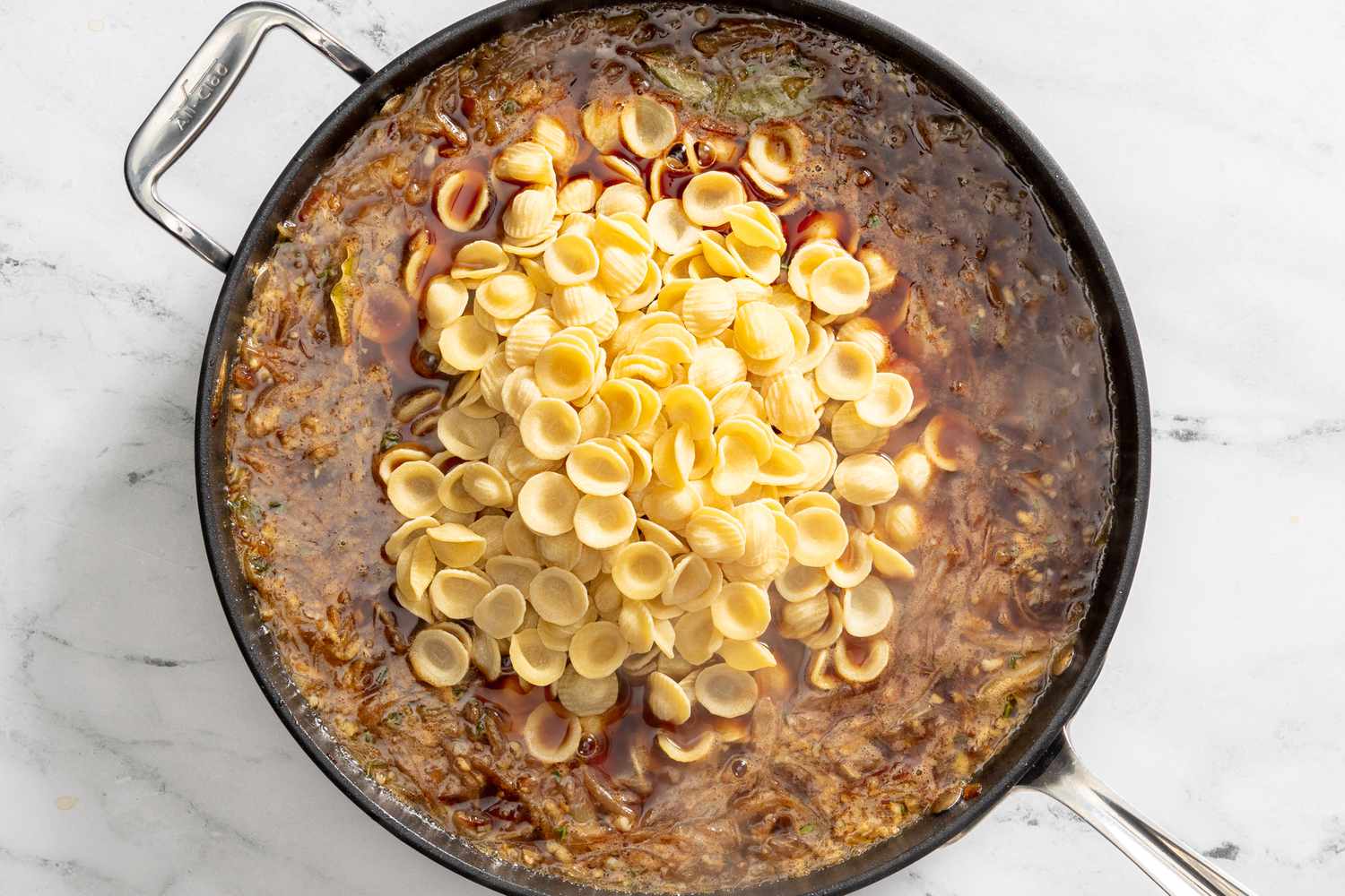 beef broth, herbs, and pasta added to pot with the caramelized onions for French onion pasta recipe