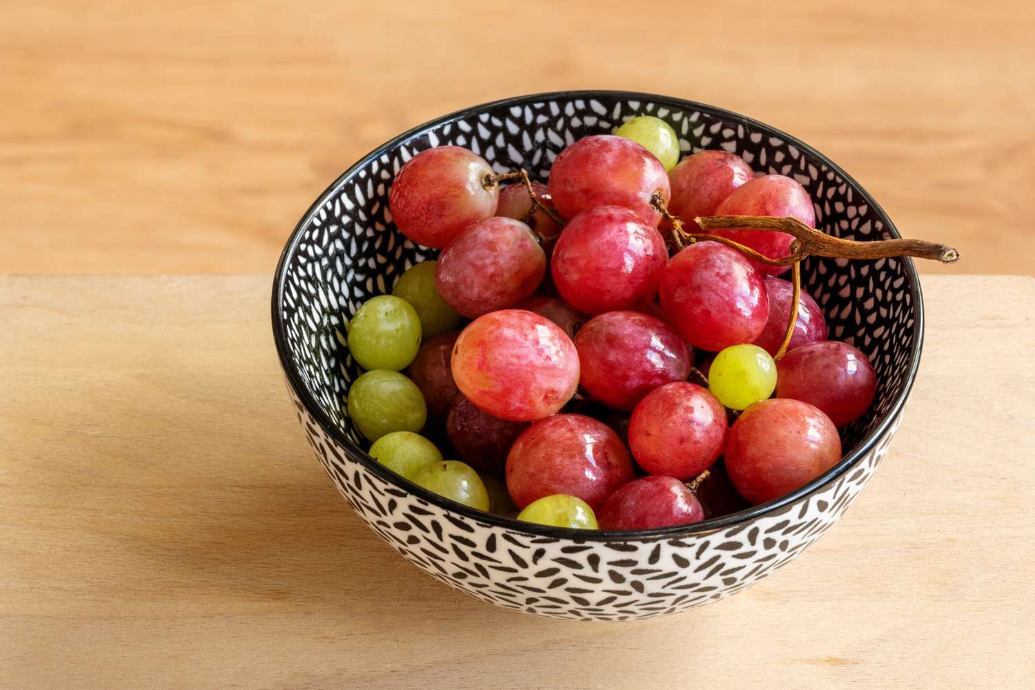 A bowl with red and green grapes