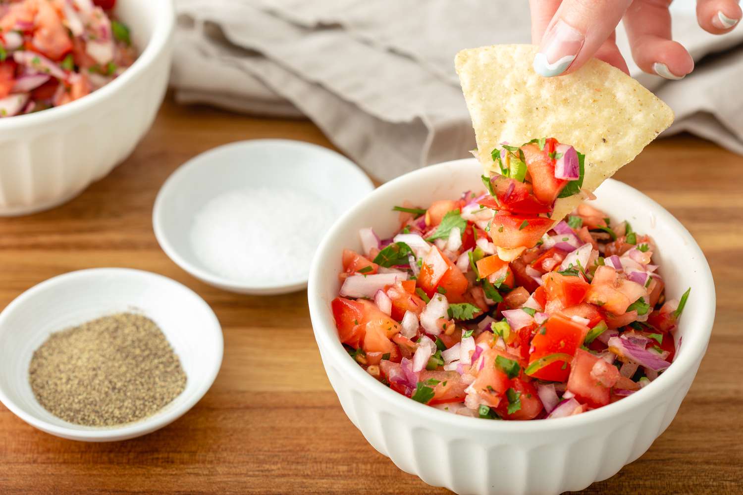 A chip dipped into tomato salsa.
