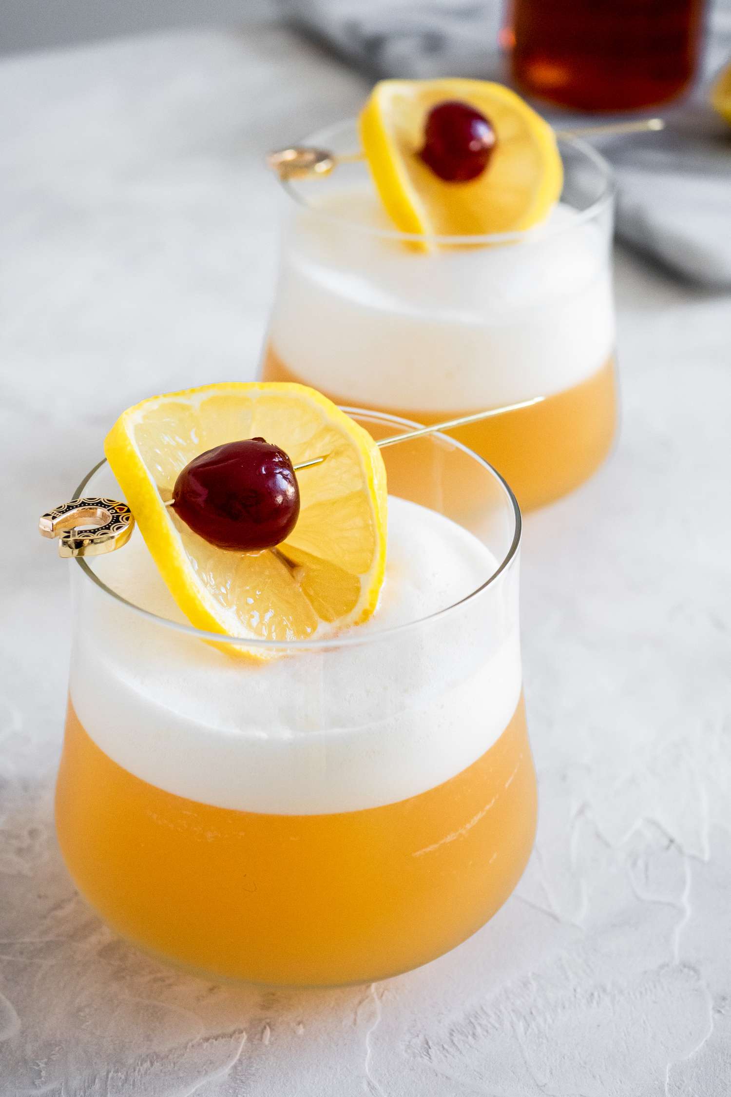 Two Glasses of Amaretto Sour Recipe Garnished with Cherry and Lemon Slice