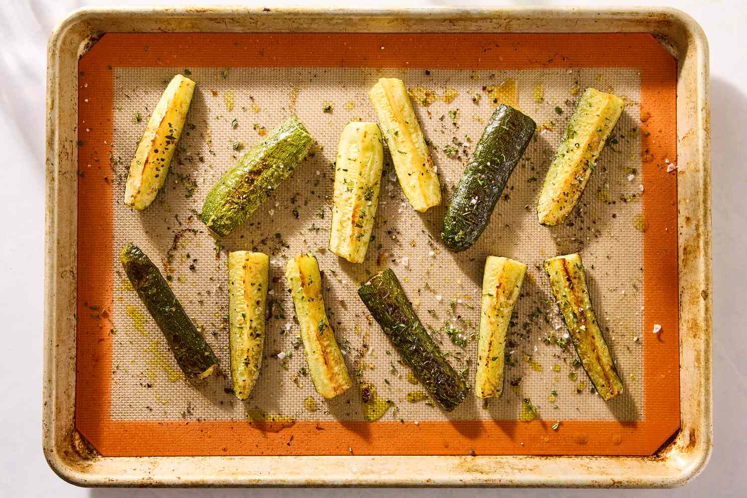 Roasted zucchini spears arranged on a baking sheet seasoned and cooked