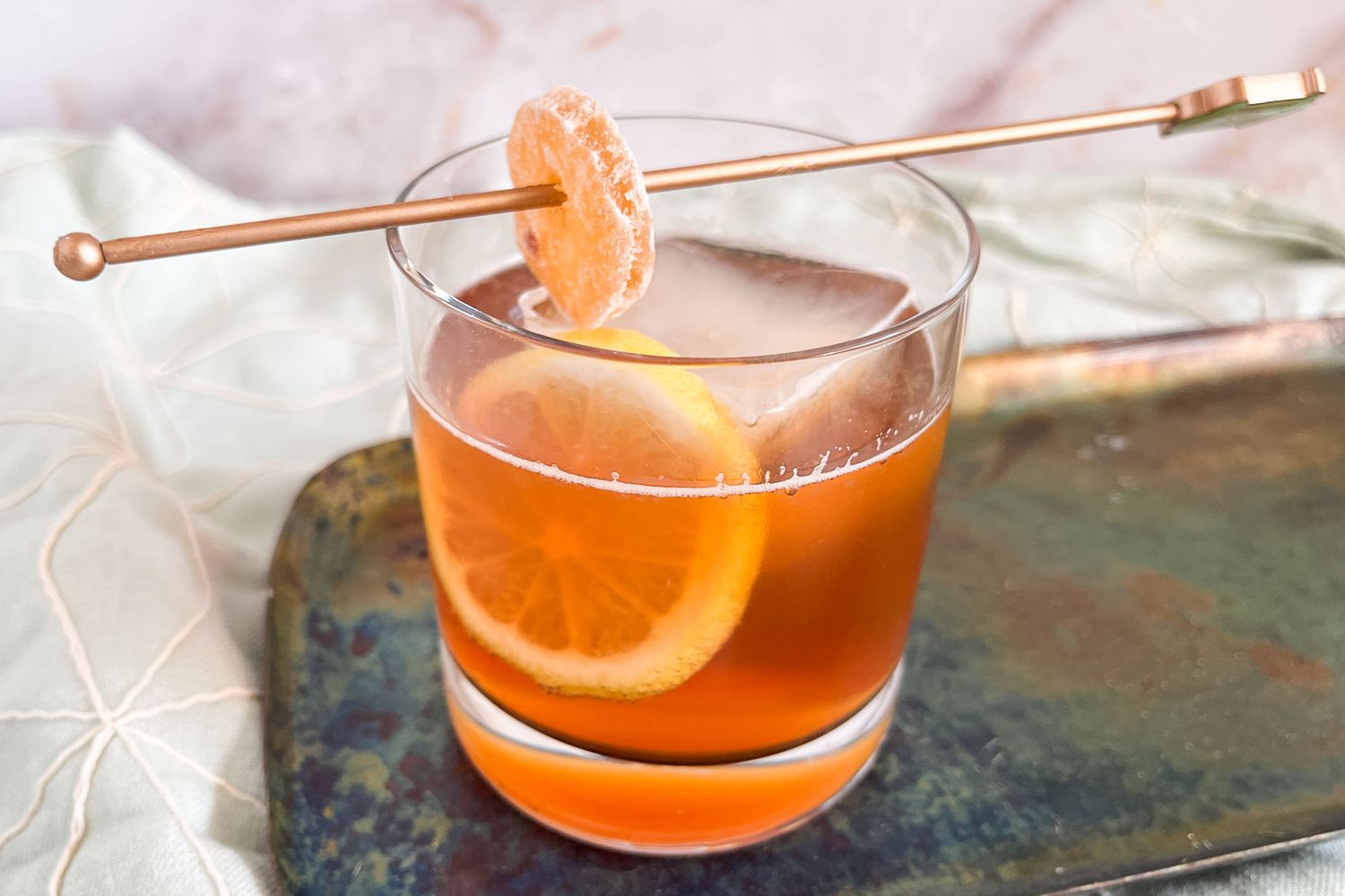 Trader Joe's spiced apple cocktail in a rocks glass garnished with candied ginger