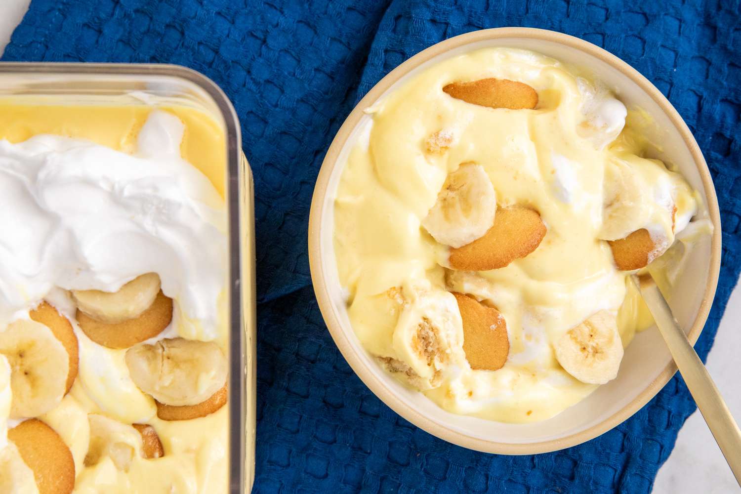 dish of Southern Banana Pudding topped with whipped cream next to a bowl of the pudding with a fork