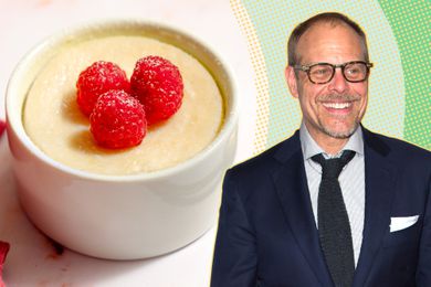 Alton Brown next to a small cheesecake in a ramekin topped with three raspberries