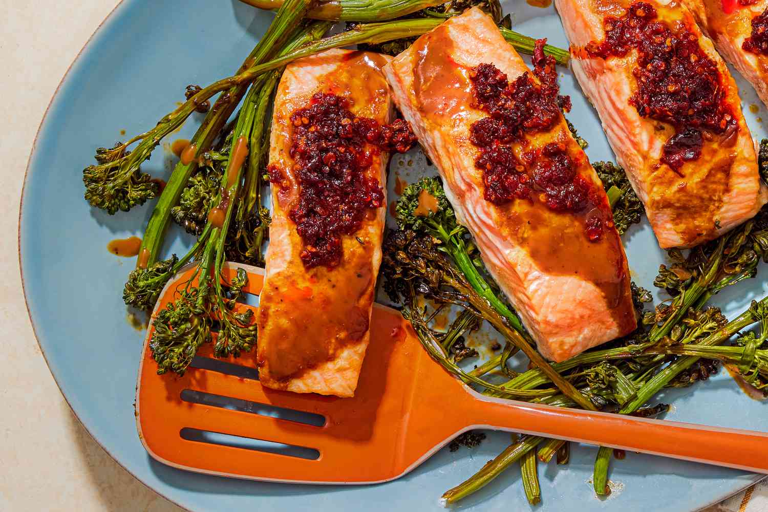 Salmon filets and broccolini topped with chile crisp on a blue plate
