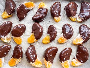 Overhead view of a parchment paper lined pan of orange slices that have been dipped in chocolate and sprinkled with salt