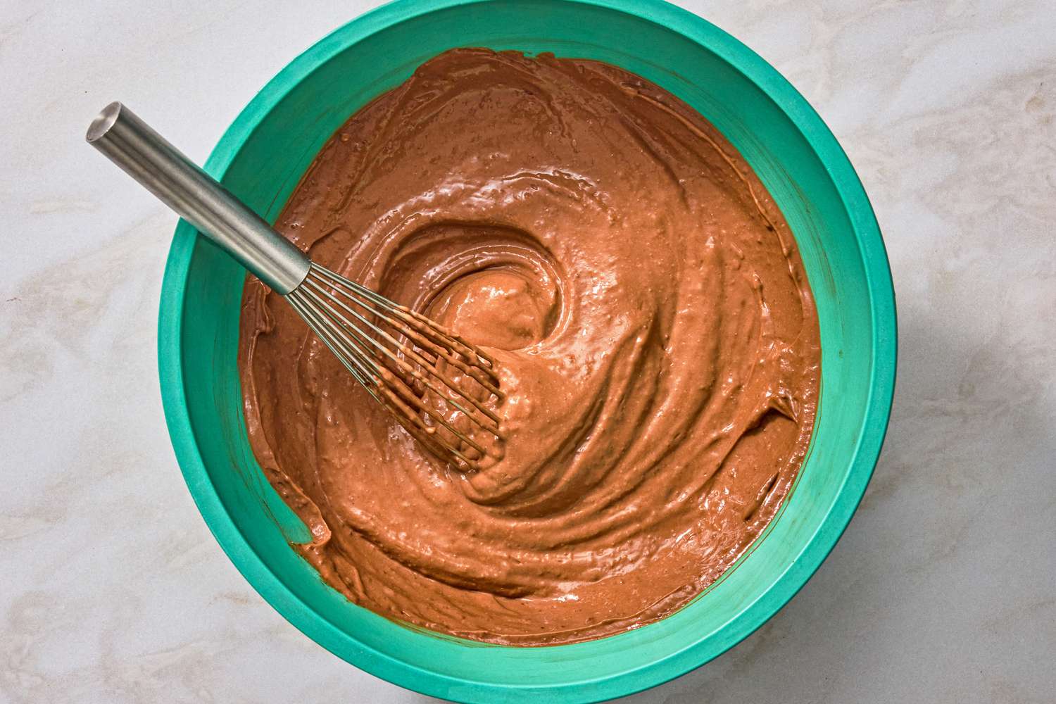 overhead view of pudding mixture in a large bowl with a whisk for Chocolate-Peanut Butter Delight