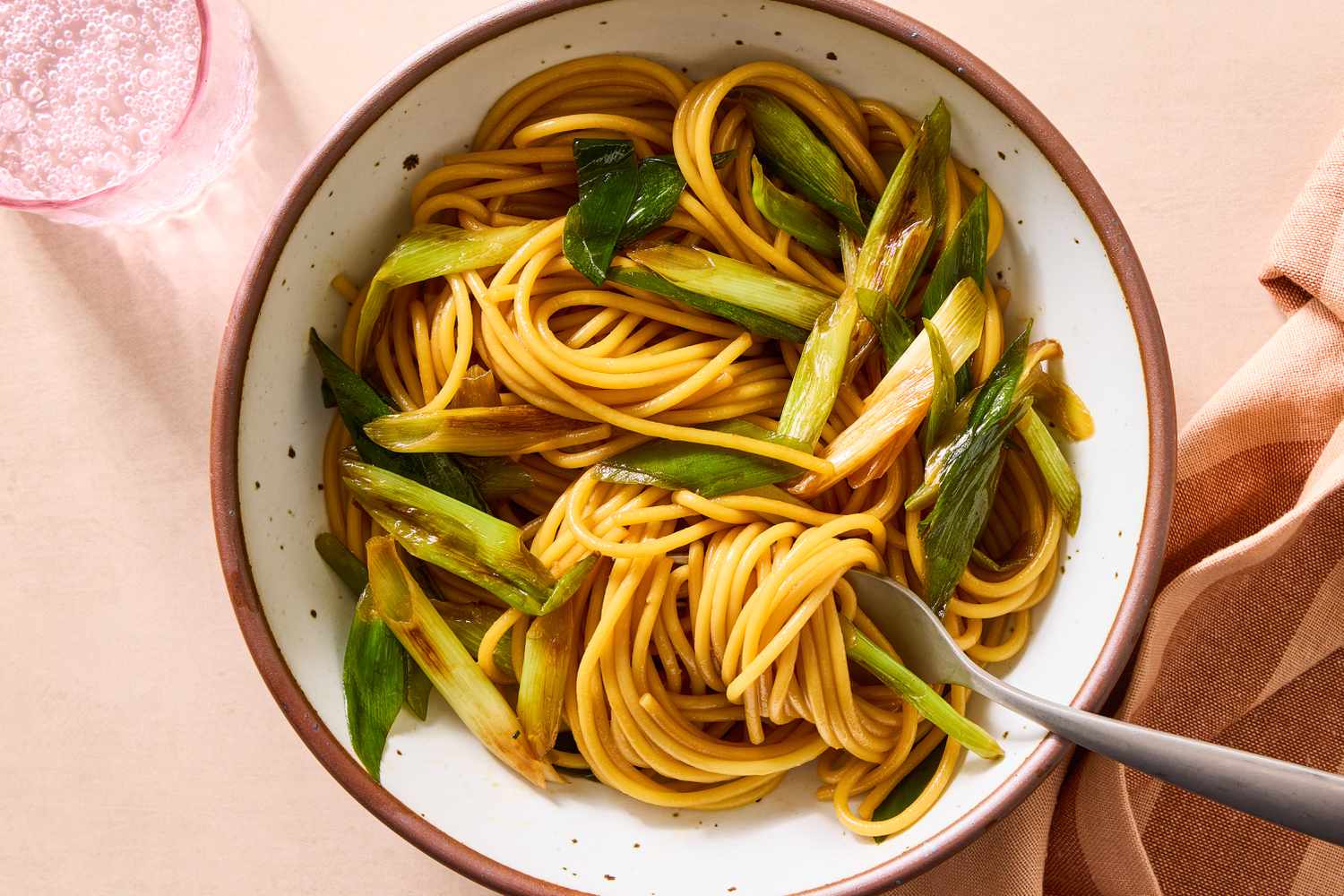 Bowl of spaghetti with scallions served with fork