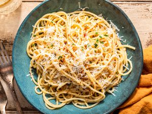 bowl of midnight pasta at a table with a drink, a table napkin, and utensils