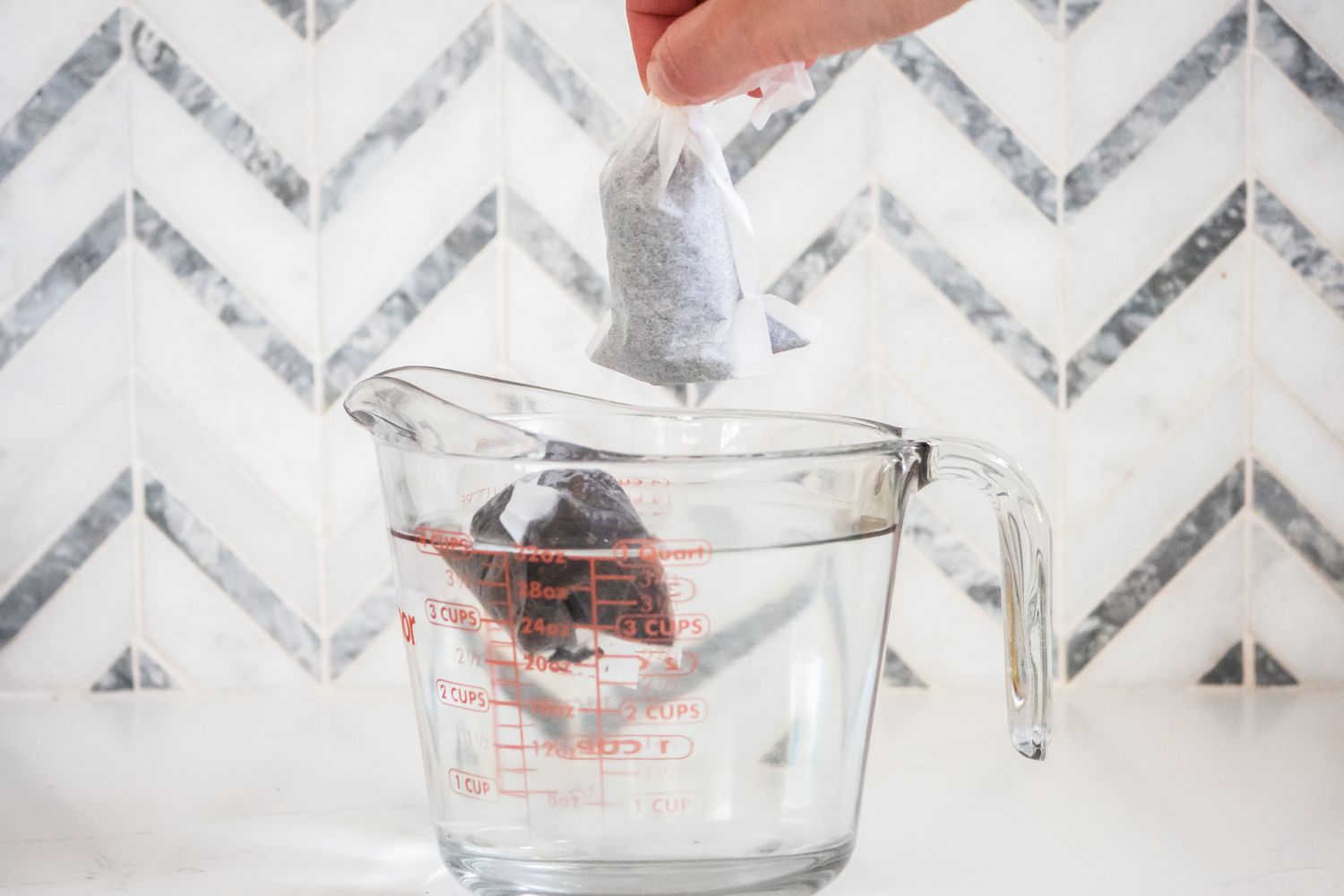 Bag of Assam Tea Added to Pyrex Measuring Cup Filled With Water for Arnold Palmer Recipe