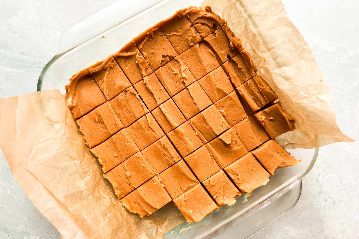 Over head view of a peanut butter fudge cut up in squares in a glass baking dish