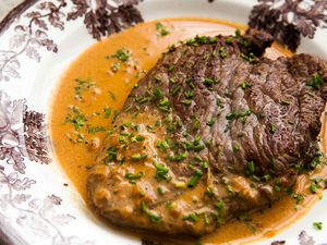 A Steak Diane resting in a sauce on a plate