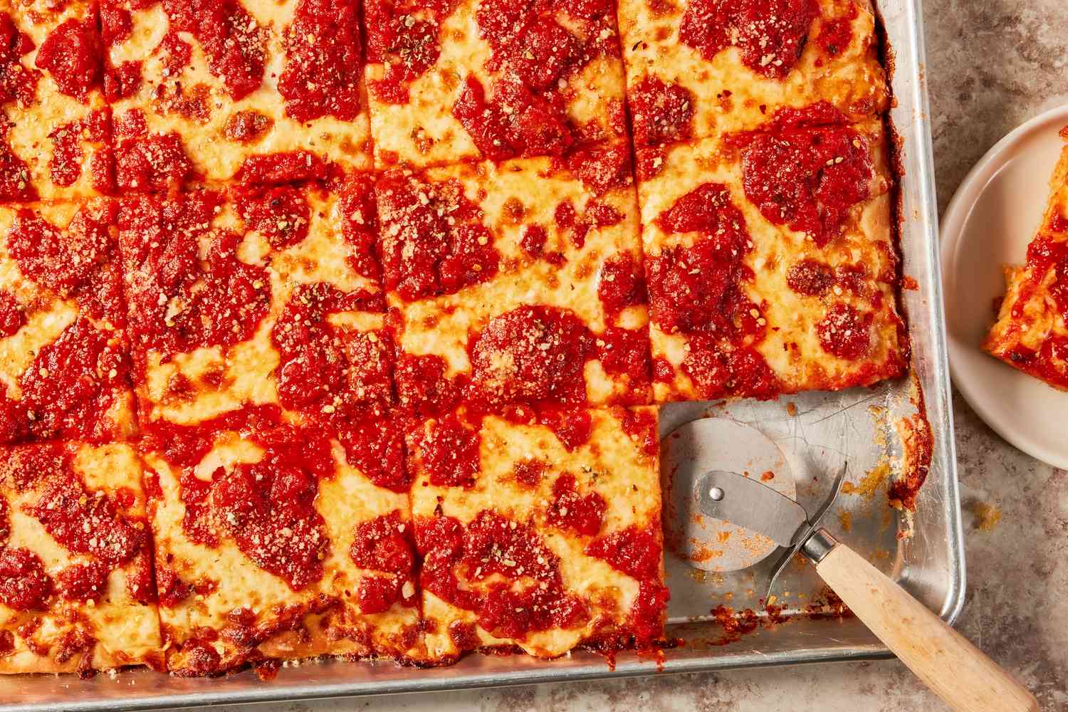 Grandma Pizza in a baking sheet cut into square pieces 