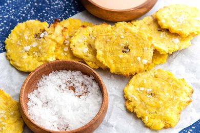 Air Fryer Tostones on parchment paper with a bowl of salt nearby.