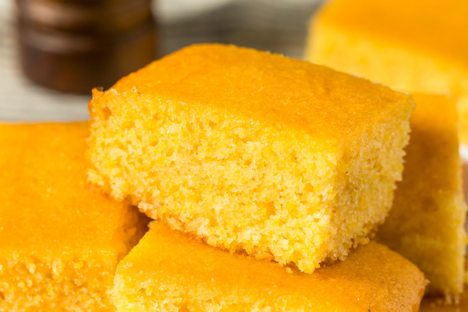 Several pieces of cornbread stacked on a dish showcasing their texture