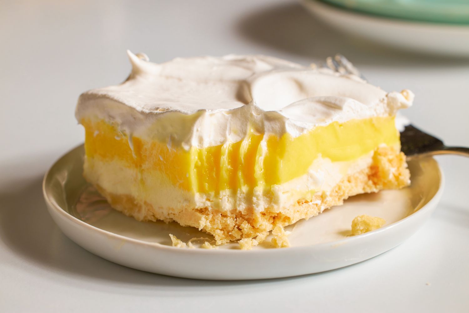 A piece of layered lemon dessert on a plate with a fork