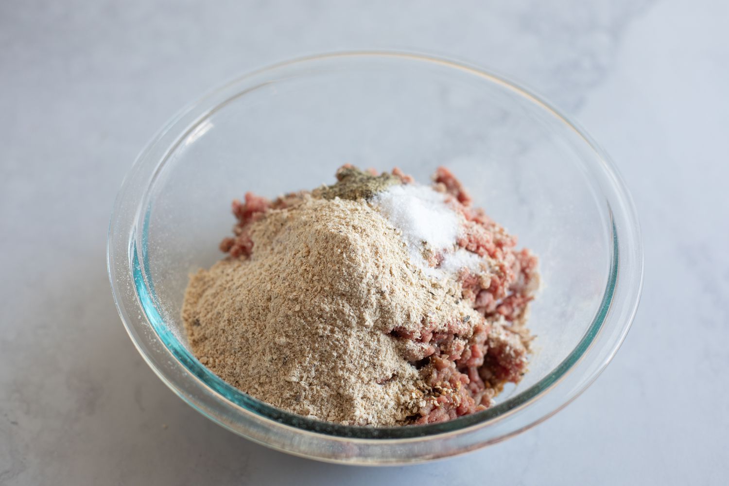 Adding ingredients to the ground beef for a mushroom swiss burger recipe.