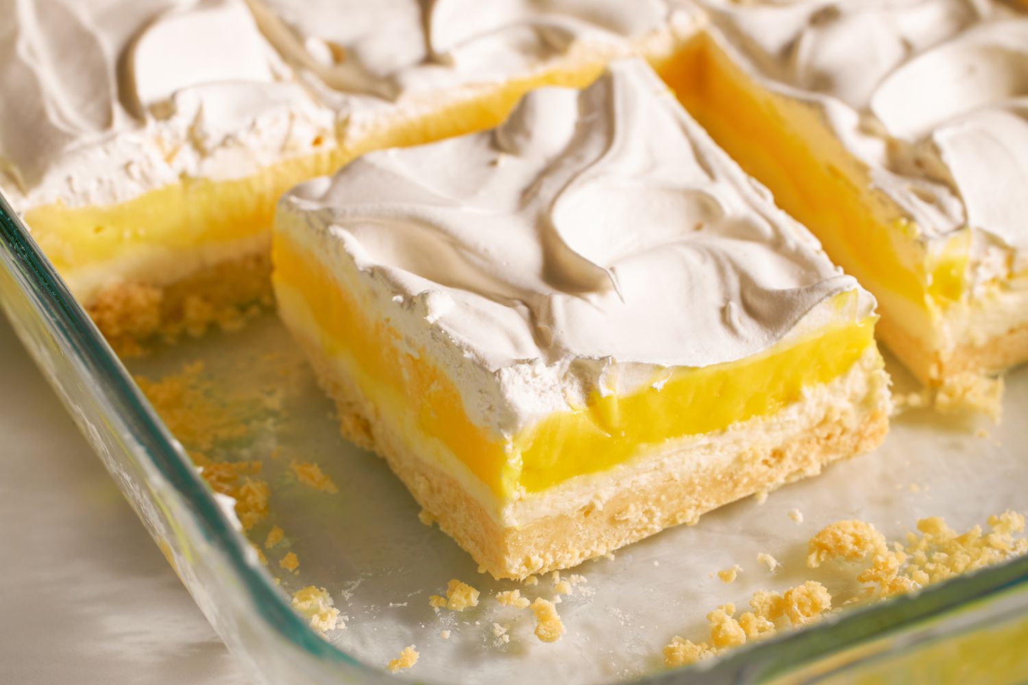 A dessert with layers of crust, lemon filling, and whipped topping in a baking dish