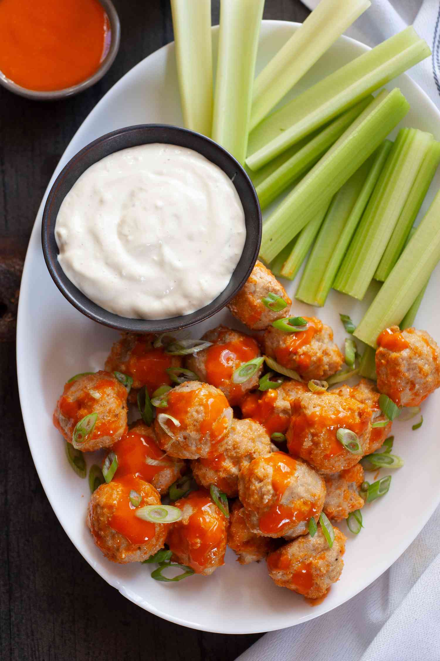 Buffalo chicken meatballs on platter with celery and blue cheese 