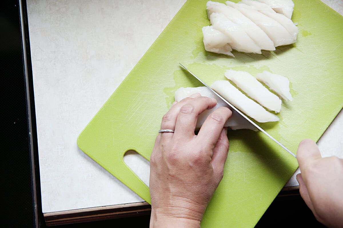  slicing cod on a cutting board for fish taco