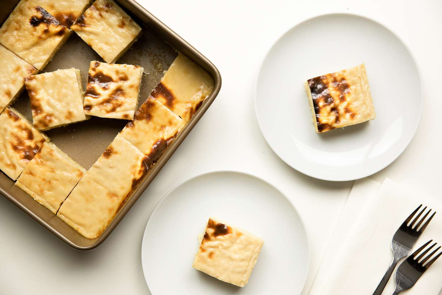 Slices of Cassava Cake on Two Plates Next to a Pan with More Cake 